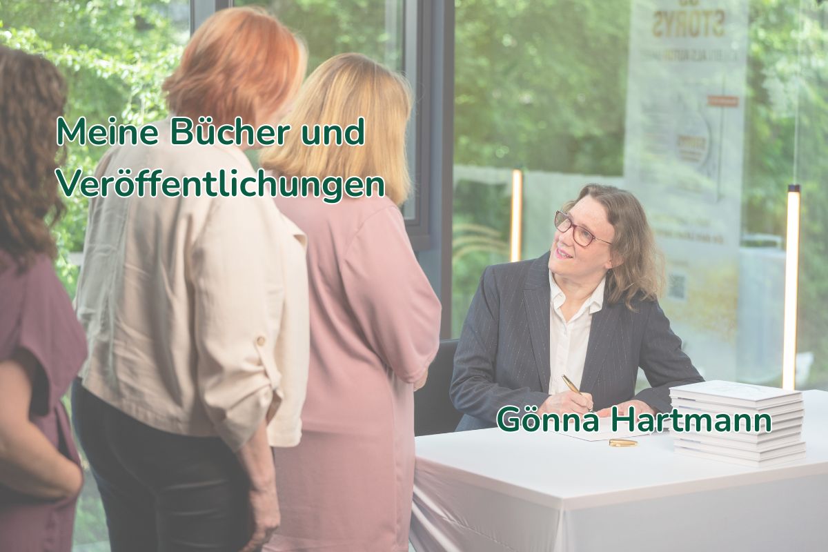 Gönna Hartmann signiert an einem Büchertisch ein Buch, neben ihr ein Stapel Bücher, davor warten drei Gäste